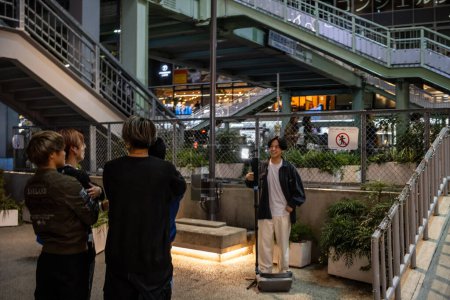 Téléchargez les photos : Tokyo, Japon, 27 octobre 2023 : Personnes debout près d'un passage supérieur piétonnier au crépuscule - en image libre de droit