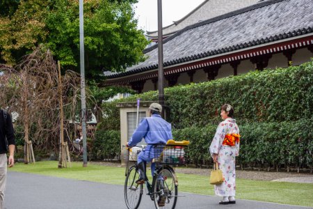Téléchargez les photos : Tokyo, Japon, 28 octobre 2023 : Une femme en kimono coloré se promène dans les jardins d'un temple bouddhiste. - en image libre de droit