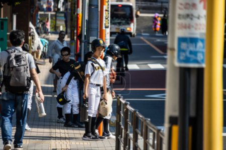 Foto de Tokio, Japón, 28 de octubre de 2023: Niños con uniformes de béisbol esperando en una parada de autobús en Tokio - Imagen libre de derechos