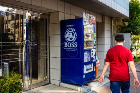 Photo for Tokyo, Japan, 28 October 2023: Man walking past a vending machine selling Suntory Boss Coffee - Royalty Free Image