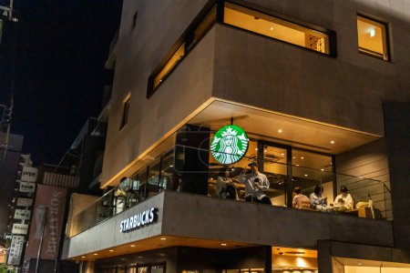 Photo for Tokyo, Japan, 29 October 2023 : Starbucks coffee shop with customers at night in a modern Tokyo neighborhood - Royalty Free Image