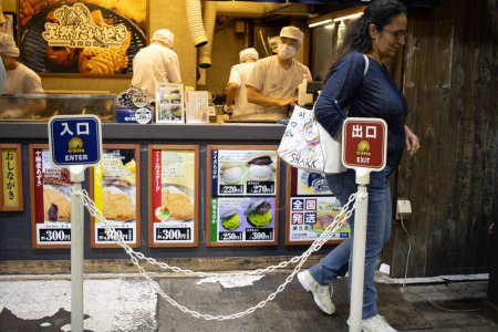 Téléchargez les photos : Tokyo, Japon, 29 octobre 2023 : Patron entrant dans un restaurant japonais avec des menus et des chefs en arrière-plan - en image libre de droit