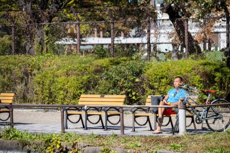 Téléchargez les photos : Tokyo, Japon, 30 octobre 2023 : Un homme assis sur un banc public dans un parc paisible - en image libre de droit