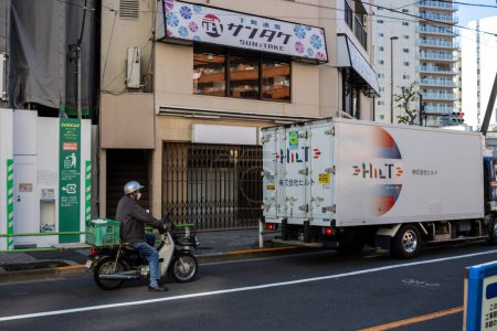 Foto de Tokio, Japón, 30 de octubre de 2023: Trabajador de reparto en bicicleta junto a un camión Yamato Transport - Imagen libre de derechos