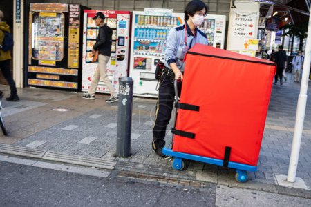 Foto de Tokio, Japón, 30 de octubre de 2023: Trabajador que transporta mercancías con un carro en Akihabara - Imagen libre de derechos