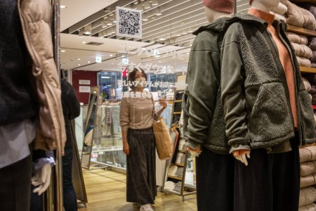 Téléchargez les photos : Tokyo, Japon, 30 Octobre 2023 : Les clients parcourant les vestes d'hiver dans un magasin de vêtements - en image libre de droit