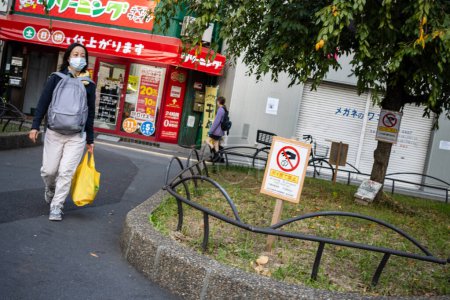 Photo for Tokyo, Japan, 31 October 2023: Pedestrian walking by a no smoking sign near a convenience store - Royalty Free Image