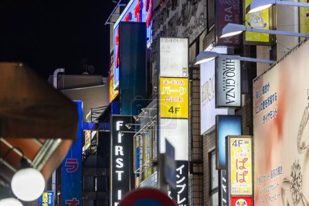 Foto de Tokio, Japón, 31 de octubre de 2023: Signos iluminados de varias tiendas y restaurantes en una calle de Tokio por la noche - Imagen libre de derechos