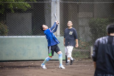 Foto de Tokio, Japón, 31 de octubre de 2023: Hombre jugando béisbol en un parque urbano con un amigo mirando - Imagen libre de derechos