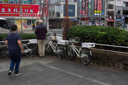Photo for Tokyo, Japan, 31 October 2023: Man walking past parked bicycles near Pachinko slot gaming parlor - Royalty Free Image
