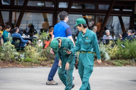 Foto de Tokio, Japón, 31 de octubre de 2023: Trabajadores del zoológico en uniforme conversando en el parque - Imagen libre de derechos