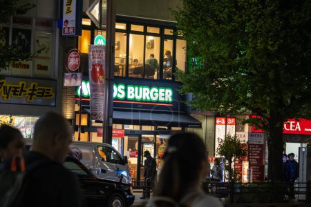 Foto de Tokio, Japón, 31 de octubre de 2023: Ocupada escena callejera con un restaurante MOS Burger por la noche - Imagen libre de derechos