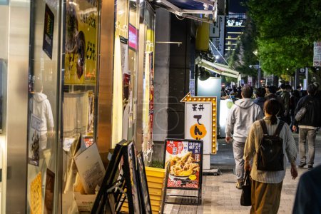 Téléchargez les photos : Tokyo, Japon, 31 octobre 2023 : Des gens marchent devant des devantures de magasins la nuit à Tokyo - en image libre de droit