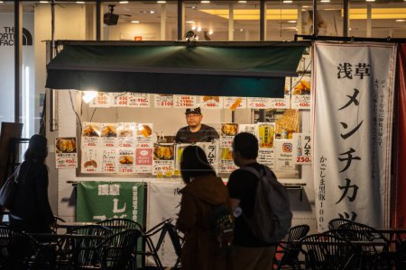 Téléchargez les photos : Tokyo, Japon, 31 Octobre 2023 : Les clients dans un stand de nourriture de rue la nuit - en image libre de droit