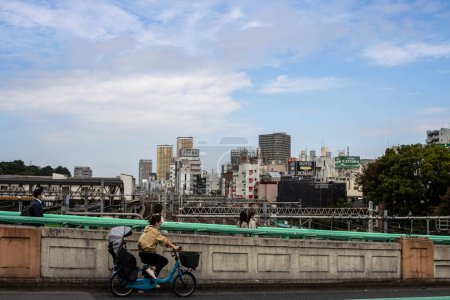 Téléchargez les photos : Tokyo, Japon, 31 octobre 2023 : Cycliste avec un passager traversant un pont à Tokyo - en image libre de droit