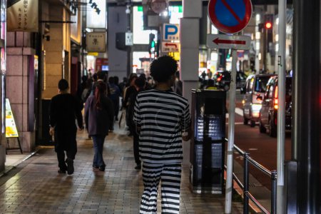 Téléchargez les photos : Tokyo, Japon, 31 octobre 2023 : Les gens marchent sur un trottoir animé de Tokyo la nuit - en image libre de droit