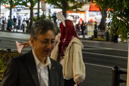 Téléchargez les photos : Tokyo, Japon, 31 octobre 2023 : Les gens marchent sur le trottoir la nuit à Tokyo - en image libre de droit