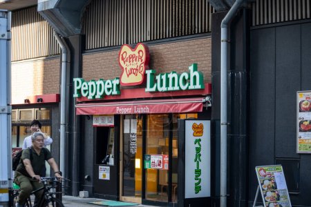 Téléchargez les photos : Tokyo, Japon, 1 Novembre 2023 : Extérieur d'un restaurant Pepper Lunch avec un cycliste passant par là - en image libre de droit