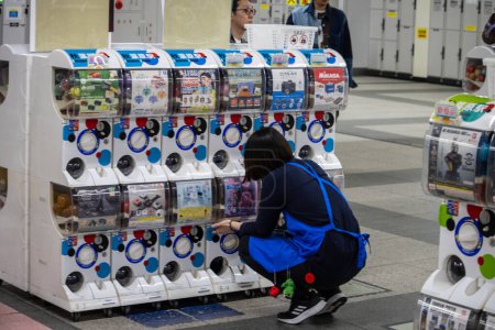 Foto de Tokio, Japón, 1 de noviembre de 2023: Persona que usa la máquina expendedora de juguetes con cápsula de Gachapon - Imagen libre de derechos
