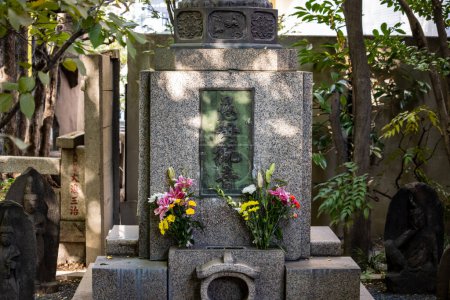 Photo for Tokyo, Japan, 1 November 2023: Traditional Japanese Grave with Fresh Flowers and Statues - Royalty Free Image
