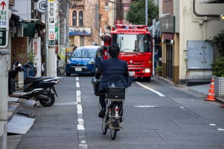 Photo for Tokyo, Japan, 1 November 2023: Cyclist and Fire Engine in Narrow Tokyo Street - Royalty Free Image