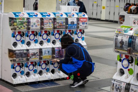 Foto de Tokio, Japón, 1 de noviembre de 2023: Persona que utiliza la máquina expendedora de juguetes cápsula en la estación de Tokio - Imagen libre de derechos