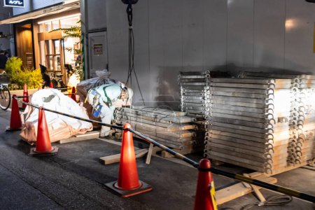 Téléchargez les photos : Tokyo, Japon, 1 Novembre 2023 : Matériaux de construction empilés sur le trottoir derrière des cônes de sécurité la nuit - en image libre de droit