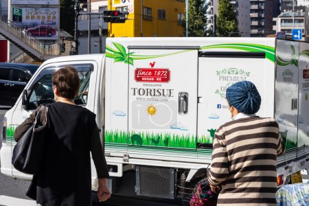 Foto de Tokio, Japón, 1 de noviembre de 2023: Personas que pasan por un camión de reparto decorado - Imagen libre de derechos