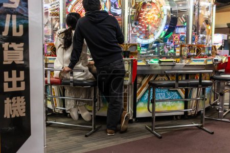 Foto de Tokio, Japón, 1 de noviembre de 2023: Pareja jugando Pachinko Machines in an Arcade - Imagen libre de derechos