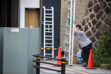 Téléchargez les photos : Tokyo, Japon, 1 Novembre 2023 : Un homme installe une échelle à l'extérieur d'un bâtiment - en image libre de droit