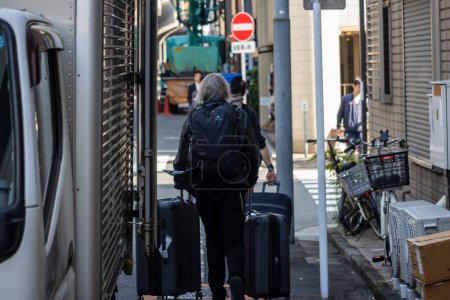 Téléchargez les photos : Tokyo, Japon, 1 Novembre 2023 : Touristes avec bagages naviguant dans les ruelles de Tokyo - en image libre de droit