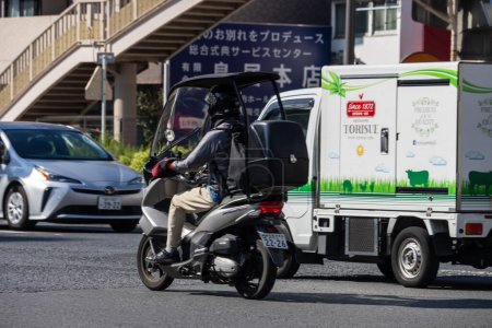 Photo for Tokyo, Japan, 1 November 2023: Delivery Worker on Motorcycle in Traffic - Royalty Free Image
