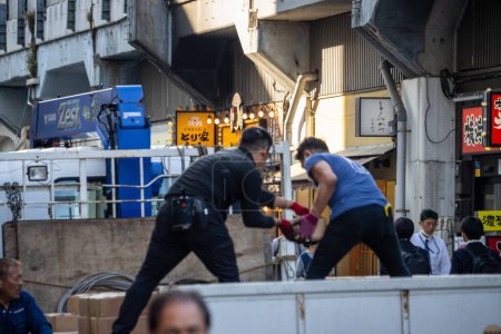 Foto de Tokio, Japón, 1 de noviembre de 2023: Trabajadores descargando mercancías de un camión en un callejón - Imagen libre de derechos