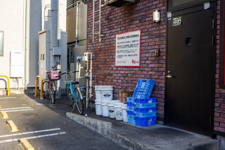 Foto de Tokio, Japón, 1 de noviembre de 2023: Vista trasera de un restaurante con bicicletas y cajas de almacenamiento azules - Imagen libre de derechos