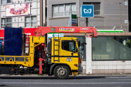 Téléchargez les photos : Tokyo, Japon, 1 Novembre 2023 : Camion de livraison jaune stationné dans une rue de la ville avec du matériel de construction - en image libre de droit
