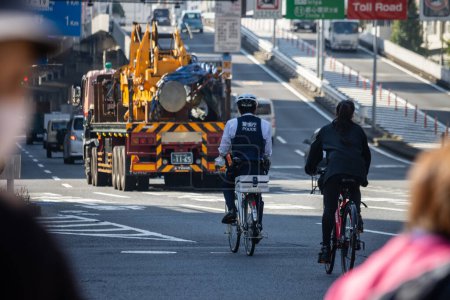 Téléchargez les photos : Tokyo, Japon, 1 Novembre 2023 : Cyclistes sur la route avec des véhicules de construction en arrière-plan - en image libre de droit