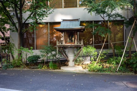 Photo for Tokyo, Japan, 1 November 2023: Traditional small Shinto shrine surrounded by plants in urban setting - Royalty Free Image