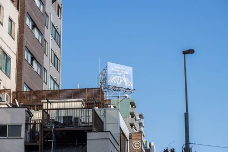 Photo for Tokyo, Japan, 1 November 2023: Prominent billboard advertising Shoei helmets atop a building in a clear blue sky - Royalty Free Image