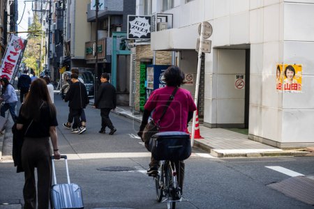 Photo for Tokyo, Japan, 1 November 2023: Pedestrians and cyclists on busy city street - Royalty Free Image