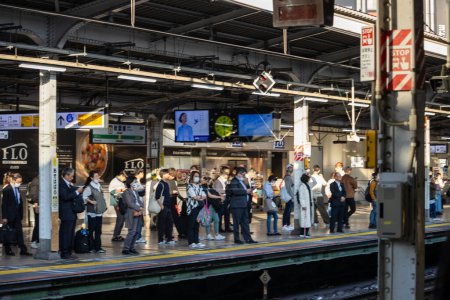 Photo for Tokyo, Japan, 1 November 2023: Commuters waiting at a busy train station platform during morning rush hour - Royalty Free Image