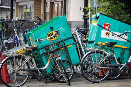 Foto de Tokio, Japón, 2 de noviembre de 2023: Entrega de bicicletas con cajas de carga verdes estacionadas en la calle - Imagen libre de derechos