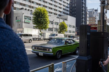 Foto de Tokio, Japón, 2 de noviembre de 2023: Coche verde clásico que pasa por edificios modernos - Imagen libre de derechos
