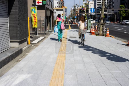 Téléchargez les photos : Tokyo, Japon, 2 novembre 2023 : Piétons et cyclistes sur le trottoir près des boutiques colorées - en image libre de droit