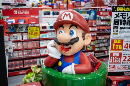 Foto de Tokio, Japón, 2 de noviembre de 2023: Mario figura frente a una tienda de electrónica con varios aparatos - Imagen libre de derechos