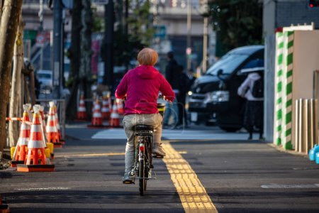 Téléchargez les photos : Tokyo, Japon, 2 Novembre 2023 : Cycliste dans la rue de la ville avec des barrières de construction - en image libre de droit