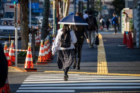 Téléchargez les photos : Tokyo, Japon, 2 novembre 2023 : Femme traversant la rue avec un parapluie - en image libre de droit
