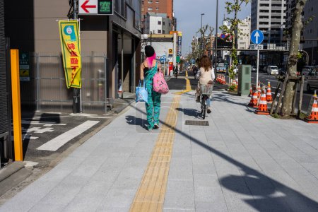 Téléchargez les photos : Tokyo, Japon, 2 novembre 2023 : Piétons et cyclistes par une journée ensoleillée dans la rue Tokyo - en image libre de droit