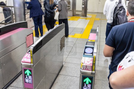 Foto de Tokio, Japón, 2 de noviembre de 2023: Viajeros que pasan por las puertas automáticas de los billetes en una estación de tren - Imagen libre de derechos