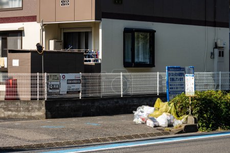 Photo for Tokyo, Japan, 3 November 2023: Residential building with a signboard and garbage collection point - Royalty Free Image