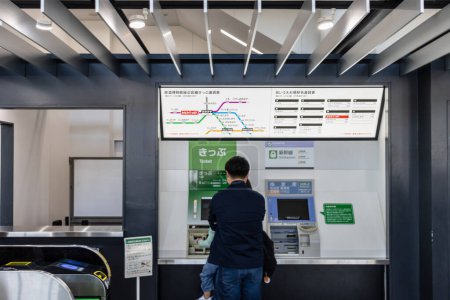 Téléchargez les photos : Tokyo, Japon, 3 novembre 2023 : Un homme interagit avec un distributeur automatique de billets dans une gare - en image libre de droit
